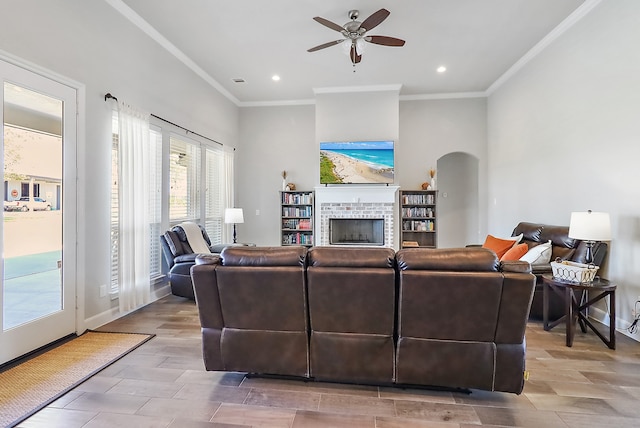 living room featuring ceiling fan, ornamental molding, light wood-type flooring, and a brick fireplace