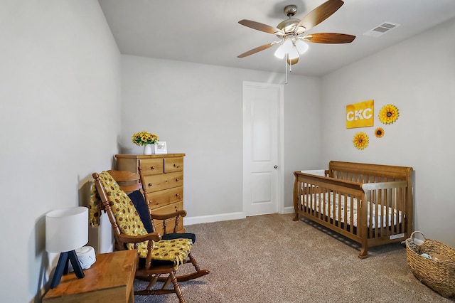 carpeted bedroom featuring ceiling fan and a nursery area