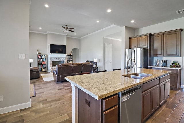 kitchen with ceiling fan, sink, wood-type flooring, a center island with sink, and appliances with stainless steel finishes