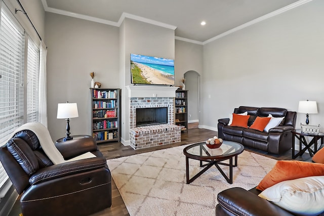 living room featuring hardwood / wood-style floors, crown molding, and a brick fireplace