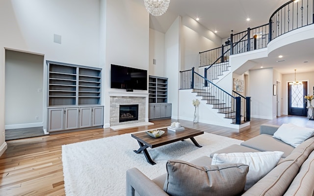 living room with light hardwood / wood-style floors, a fireplace, a high ceiling, and a chandelier