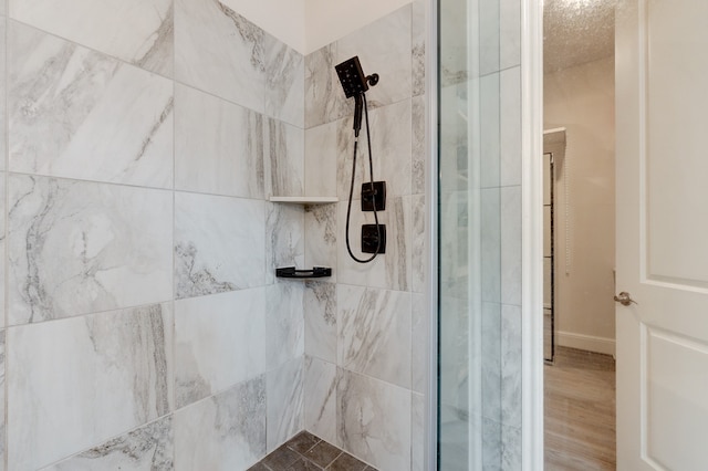 bathroom with a tile shower and hardwood / wood-style flooring