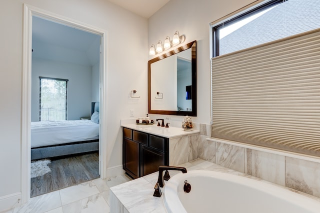 bathroom featuring tiled tub, a wealth of natural light, and vanity