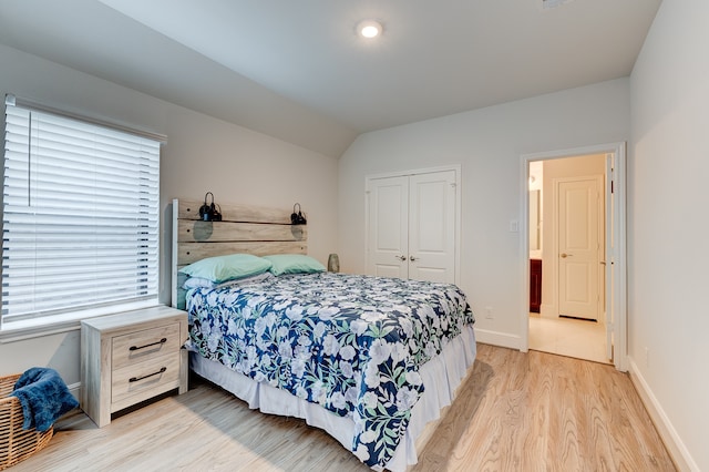 bedroom with light hardwood / wood-style floors, a closet, and lofted ceiling