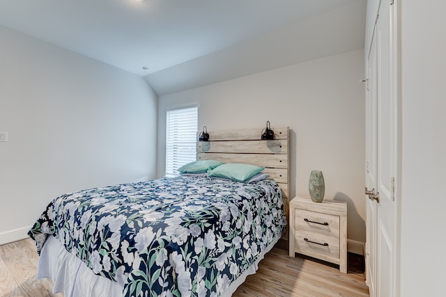 bedroom featuring lofted ceiling and light wood-type flooring