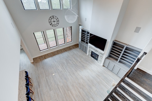 living room featuring a fireplace, an inviting chandelier, a high ceiling, and hardwood / wood-style flooring