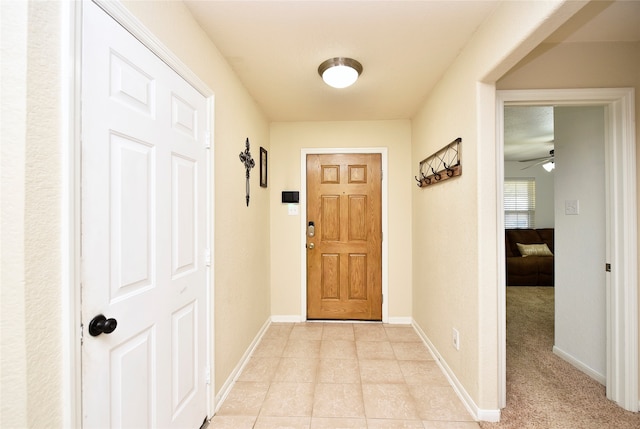 doorway featuring ceiling fan and light colored carpet