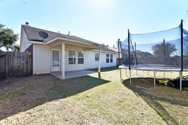 rear view of house featuring a lawn, a trampoline, and a patio