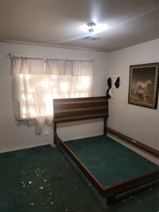 unfurnished bedroom featuring a textured ceiling and dark carpet