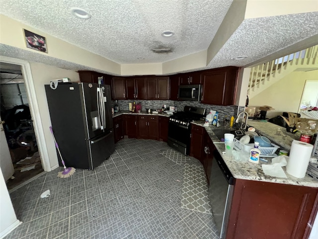 kitchen with sink, decorative backsplash, appliances with stainless steel finishes, a textured ceiling, and light stone counters