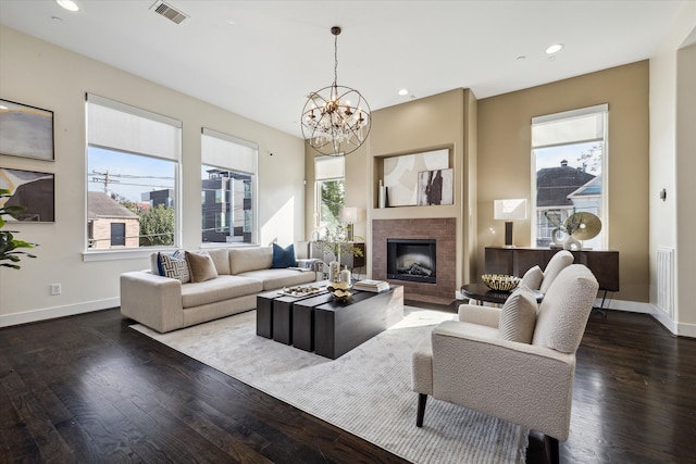 living room featuring a wealth of natural light, dark wood-type flooring, and an inviting chandelier