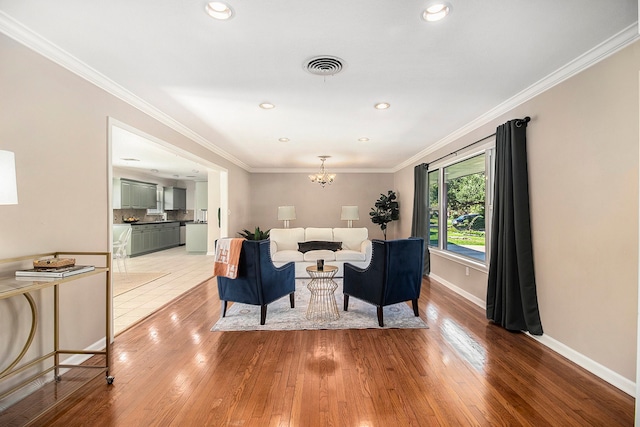 living room featuring hardwood / wood-style floors, ornamental molding, and an inviting chandelier