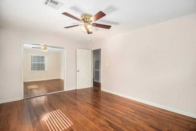 unfurnished bedroom featuring ceiling fan, a closet, and dark wood-type flooring