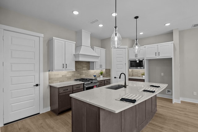 16022 Mason Run Dr, Houston, TX 77079 - kitchen with baseboards, custom exhaust hood, a sink, white cabinets, and appliances with stainless steel finishes