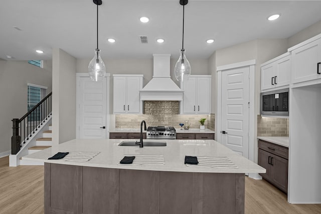 16022 Mason Run Dr, Houston, TX 77079 - kitchen featuring light wood-style floors, built in microwave, a sink, and custom range hood