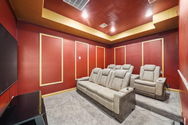 carpeted home theater room with a tray ceiling