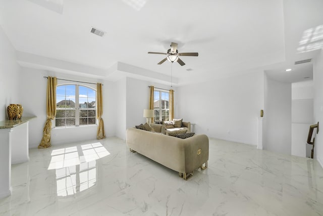 unfurnished living room featuring a tray ceiling and ceiling fan