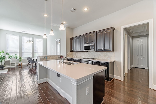 kitchen featuring appliances with stainless steel finishes, backsplash, dark brown cabinetry, sink, and pendant lighting