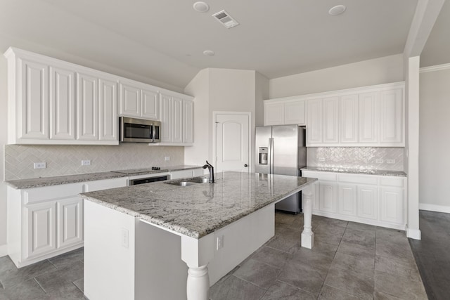 kitchen featuring tasteful backsplash, stainless steel appliances, sink, white cabinets, and an island with sink