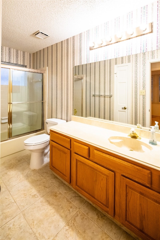 full bathroom with vanity, toilet, bath / shower combo with glass door, and a textured ceiling