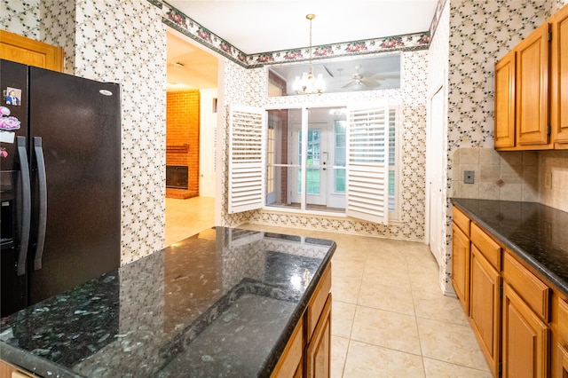 kitchen with pendant lighting, black fridge, ceiling fan, dark stone countertops, and light tile patterned flooring