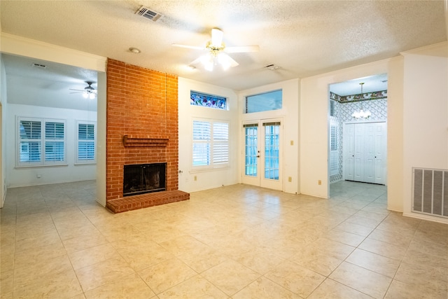 unfurnished living room featuring ceiling fan, a fireplace, light tile patterned floors, and a textured ceiling