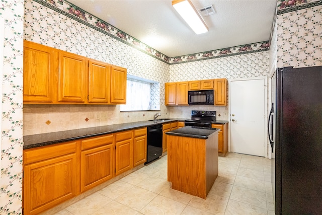 kitchen with sink, black appliances, dark stone countertops, a kitchen island, and light tile patterned flooring