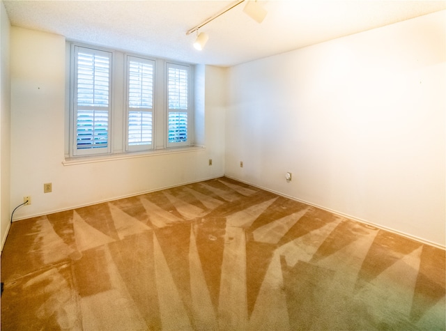 carpeted empty room with track lighting