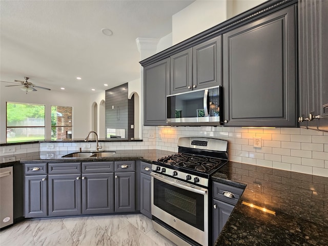 kitchen with dark stone counters, sink, ceiling fan, tasteful backsplash, and stainless steel appliances