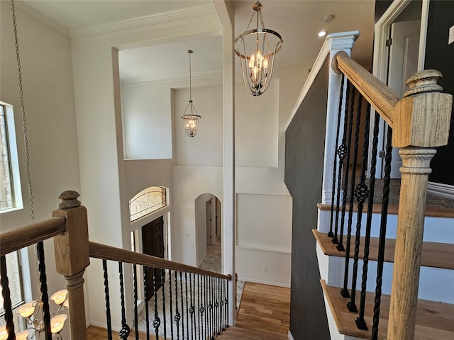 staircase with crown molding, an inviting chandelier, and hardwood / wood-style flooring