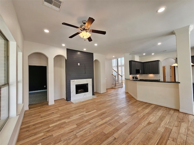 unfurnished living room featuring ceiling fan, a high end fireplace, and light hardwood / wood-style flooring