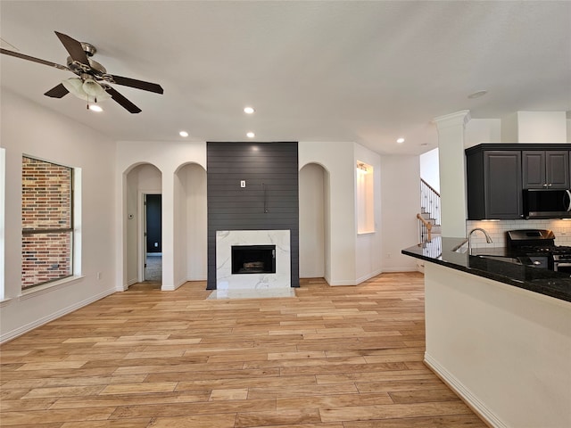 living room with a fireplace, ceiling fan, light hardwood / wood-style flooring, and sink