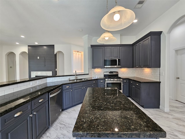 kitchen featuring stainless steel appliances, sink, dark stone countertops, a kitchen island, and hanging light fixtures