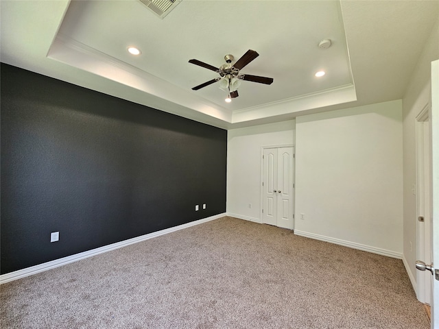 empty room featuring ceiling fan, carpet floors, ornamental molding, and a tray ceiling