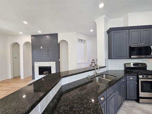 kitchen featuring decorative backsplash, sink, dark stone counters, and appliances with stainless steel finishes