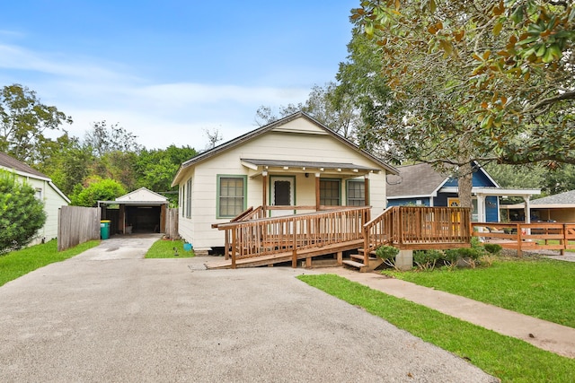 bungalow-style house featuring covered porch, a garage, an outdoor structure, and a front yard