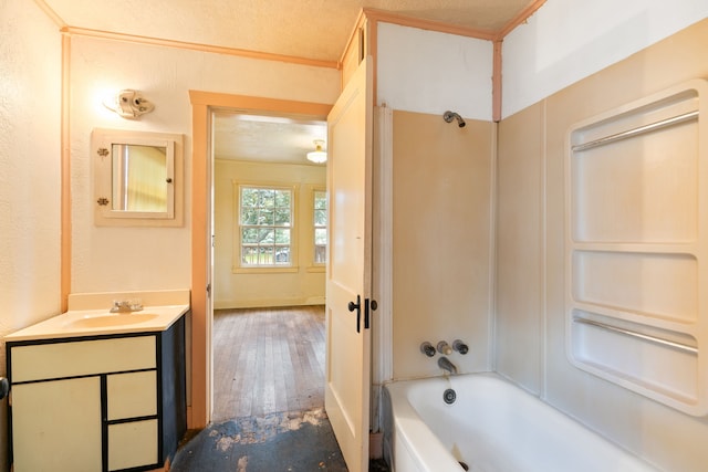 bathroom with hardwood / wood-style floors, a textured ceiling, vanity, bathtub / shower combination, and ornamental molding