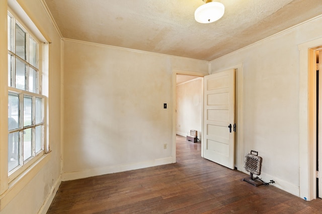 spare room featuring a textured ceiling, dark hardwood / wood-style flooring, and ornamental molding