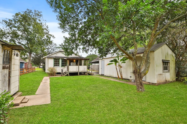 rear view of house featuring a deck, a storage unit, and a lawn