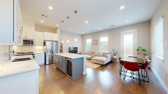 kitchen with white cabinetry, a center island, wine cooler, appliances with stainless steel finishes, and hardwood / wood-style flooring