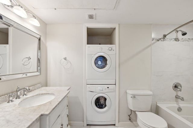 full bathroom featuring vanity, toilet, tiled shower / bath, and stacked washer / drying machine