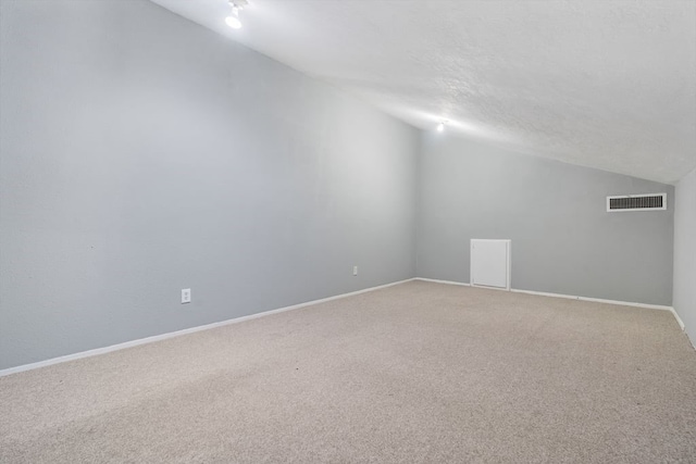 carpeted empty room featuring a textured ceiling and vaulted ceiling