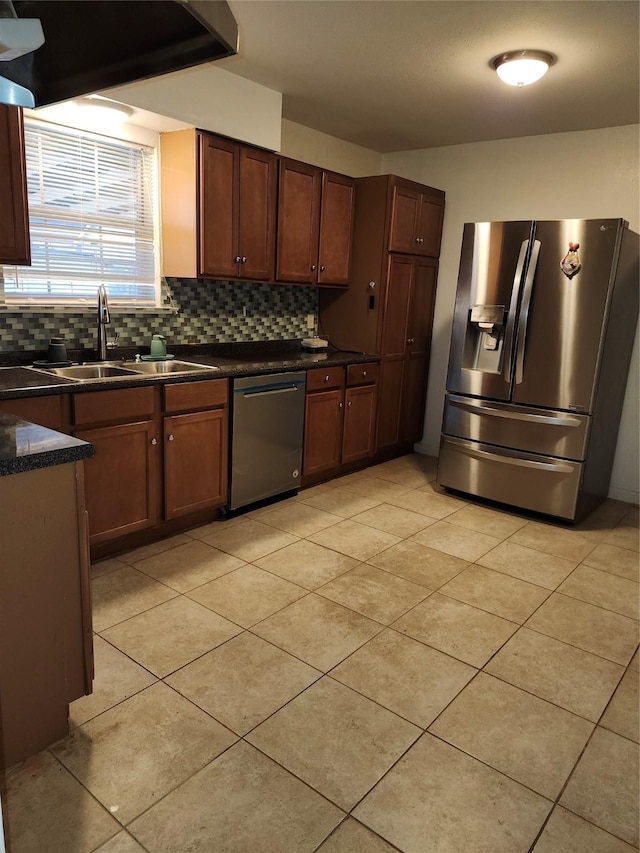 kitchen featuring decorative backsplash, dark countertops, ventilation hood, stainless steel appliances, and a sink