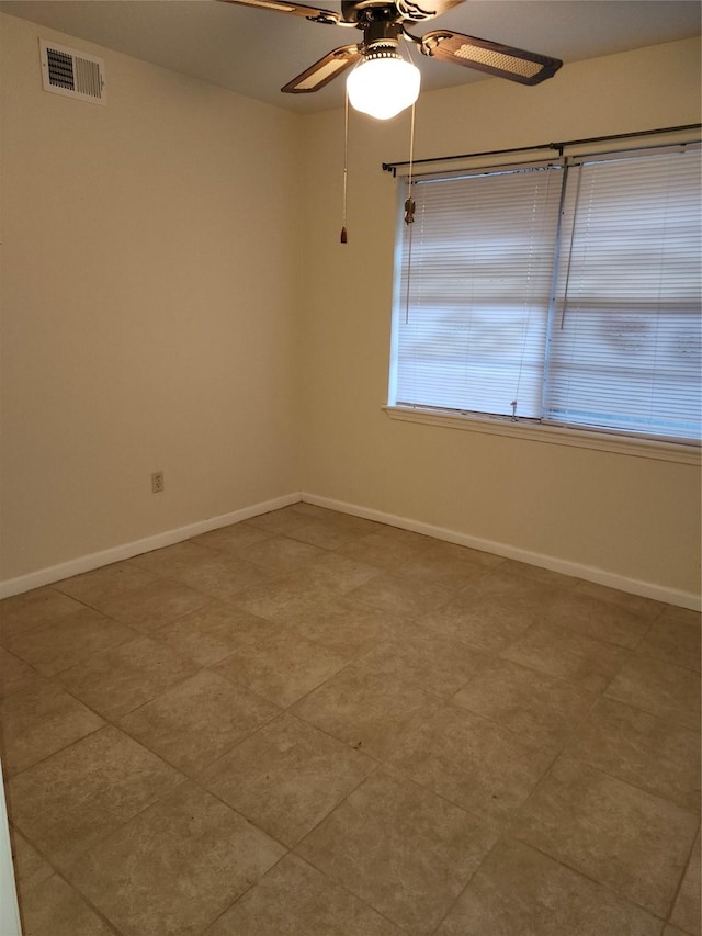 empty room featuring ceiling fan, visible vents, and baseboards