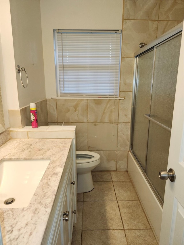 full bath featuring toilet, tile patterned flooring, bath / shower combo with glass door, and vanity