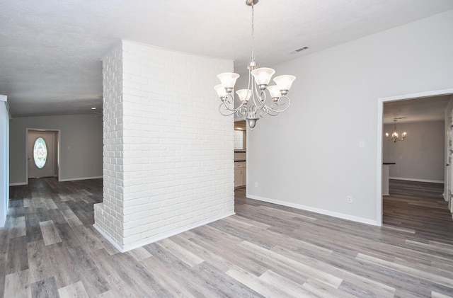 unfurnished dining area featuring an inviting chandelier and hardwood / wood-style flooring