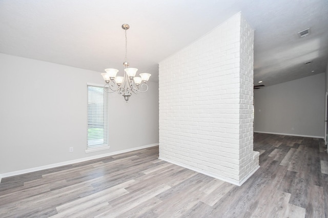 empty room with hardwood / wood-style flooring, lofted ceiling, and an inviting chandelier