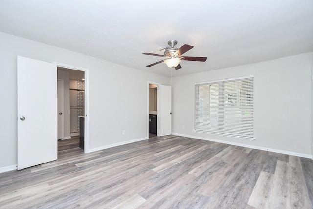 unfurnished bedroom with ceiling fan, connected bathroom, and light wood-type flooring