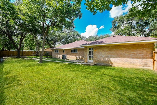 back of house featuring a yard and central AC