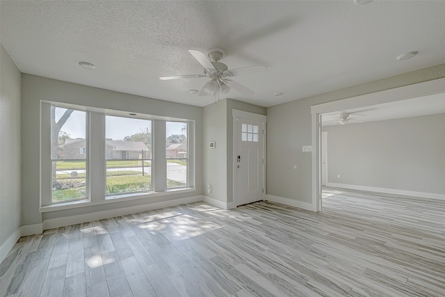 foyer entrance with ceiling fan, light hardwood / wood-style floors, and a textured ceiling